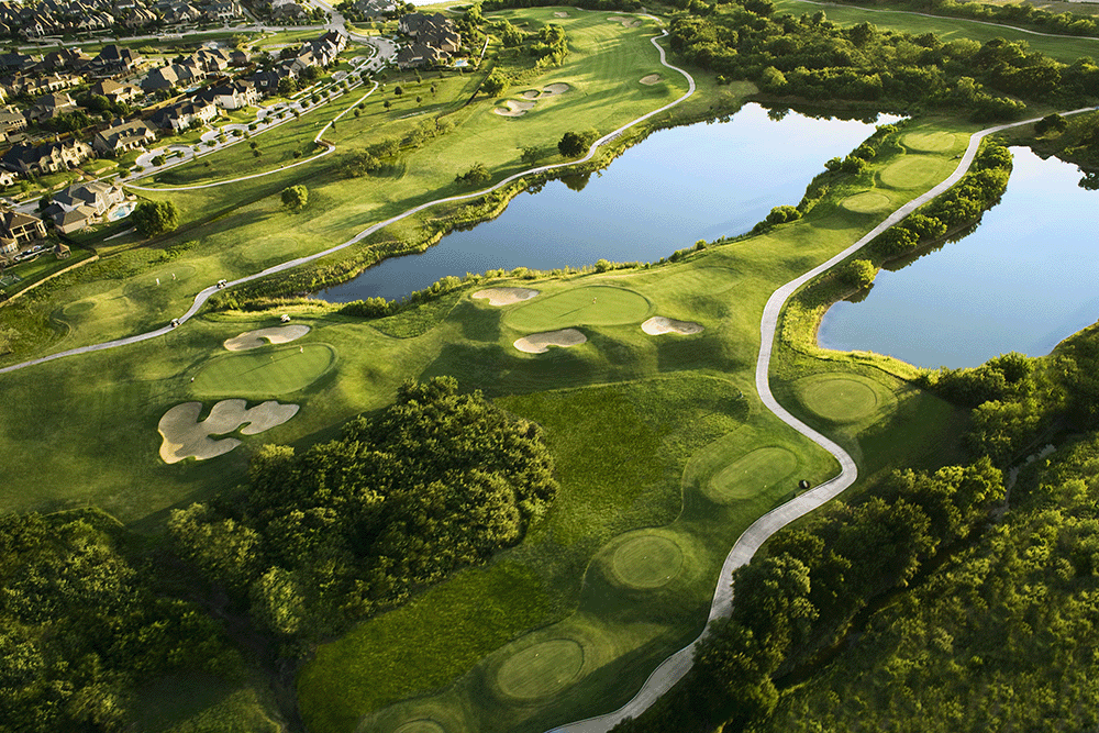 Green trees and a lake and an 18-hole golf course aerial view